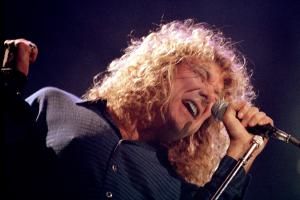 Close-up of Robert Plant singing into a microphone during a concert